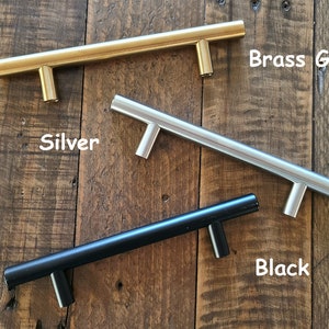 Puede incluir: Tres tiradores de armario en diferentes acabados: oro lat&oacute;n, plata y negro. Los tiradores son todos del mismo tama&ntilde;o y forma, con un dise&ntilde;o simple y moderno.