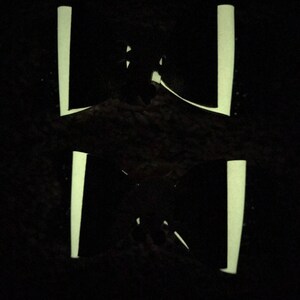 May include: A black silhouette of a person standing in front of two vertical white lines.