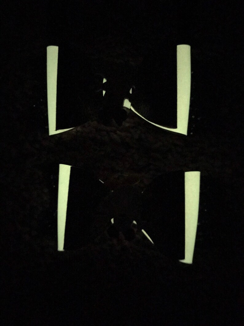 May include: A black silhouette of a person standing in front of two vertical white lines.