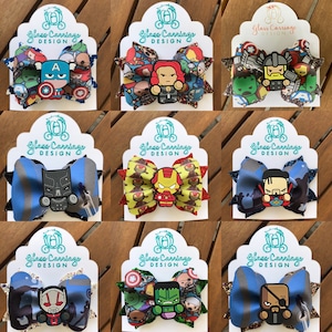 Puede incluir: Nueve lazos para el pelo hechos a mano con diferentes personajes de superhéroes de Marvel. Cada lazo está hecho con tela colorida y purpurina, y presenta un personaje diferente, incluyendo Iron Man, Capitán América, Hulk, Thor, Pantera Negra, Viuda Negra, y más.