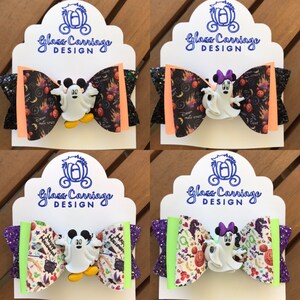 May include: Four Halloween-themed hair bows featuring a ghost Mickey Mouse and Minnie Mouse character. The bows are made with black, orange, purple, and green glitter fabric and feature a variety of Halloween-themed patterns.