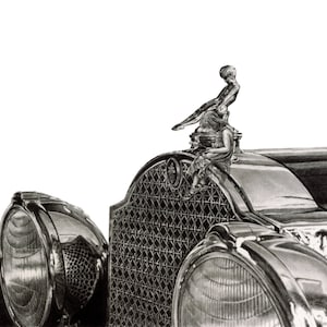 May include: A black and white drawing of a vintage car's hood ornament and front grill. The ornament features a woman in a flowing dress, standing on a bird. The grill is a detailed, intricate design.
