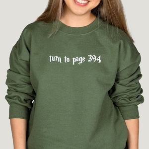 May include: A green sweatshirt with the text "turn to page 394" in white. The model is wearing a size Medium.