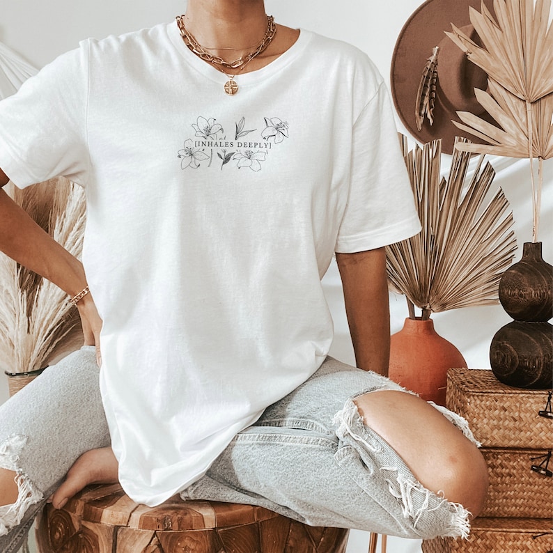 May include: White oversized t-shirt with a floral design and the text "[inhales deeply]" printed on the front.