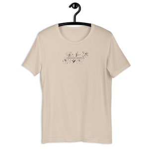 May include: A beige t-shirt with a floral design and the text "[INHALES DEEPLY]" printed on the front.