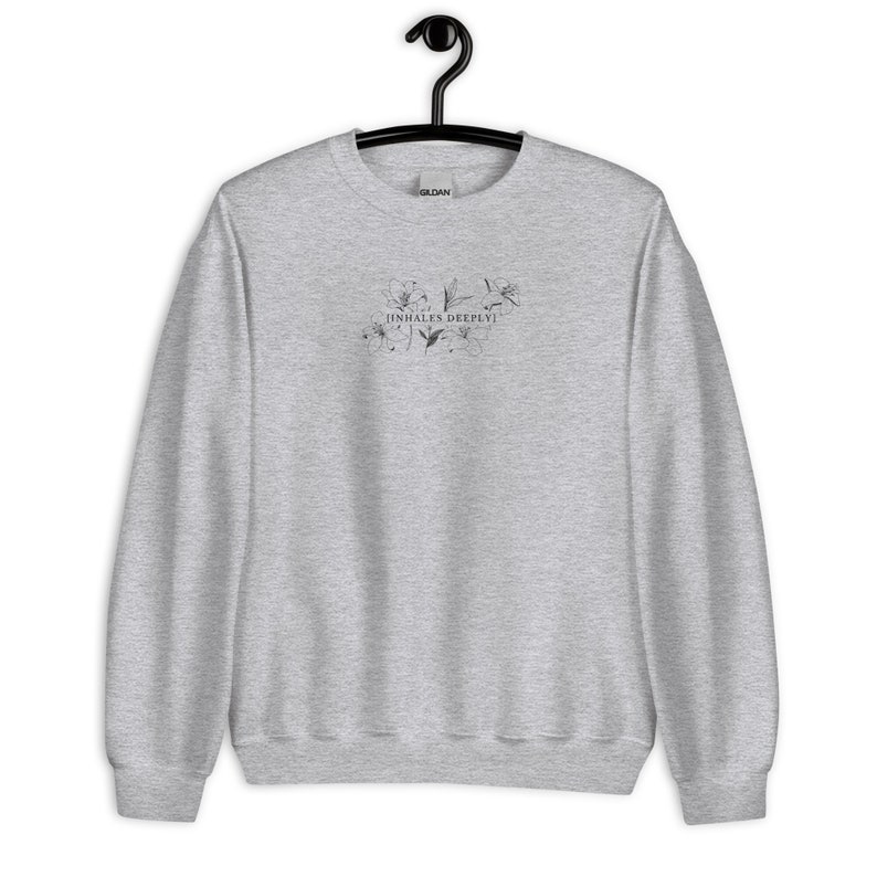 May include: A heather grey sweatshirt with a floral design and the text "inhales deeply!" printed on the front.