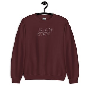 May include: Burgundy sweatshirt with a white floral design and the text "inhales deeply" on the front.