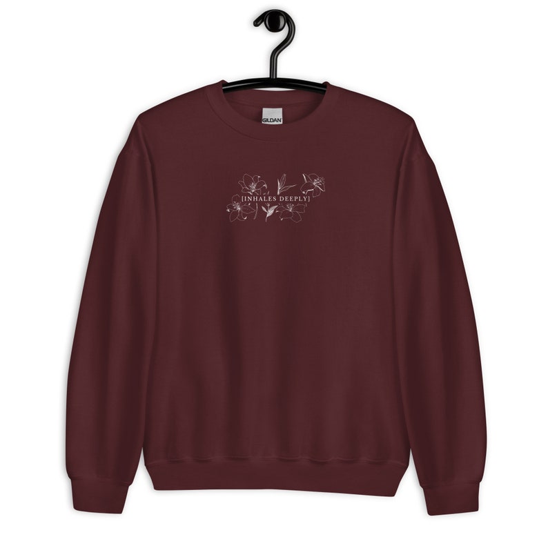 May include: Burgundy sweatshirt with a white floral design and the text "inhales deeply" on the front.