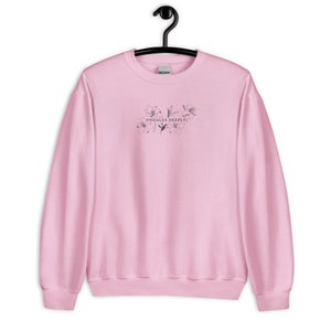 May include: A pink sweatshirt with a black floral design and the text "[inhales deeply]" printed on the front.