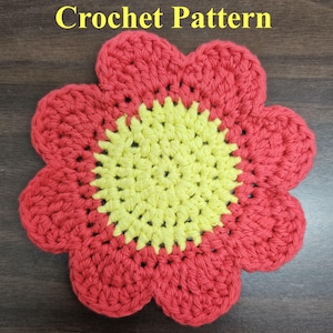 May include: A crocheted flower with a red outer layer and a yellow center. The flower is made with a single crochet stitch and has a simple design.