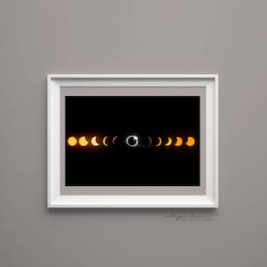Könnte beinhalten: Ein Schwarzweißfoto einer Sonnenfinsternis. Das Bild zeigt die Sonne, die von dem Mond bedeckt wird, mit einem Lichtring um den Mond. Das Bild ist in einem weißen Rahmen gerahmt.