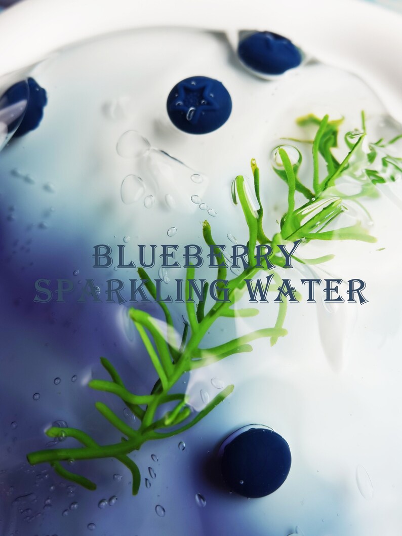 May include: A refreshing composition featuring blueberries, green sprigs, and water droplets. The text "BLUEBERRY SPARKLING WATER" is overlaid on the image, suggesting a beverage concept. The image has a cool, clean aesthetic.
