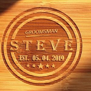 May include: A wooden plaque with a circular design, featuring the text "GROOMSMAN STEVE EST. 05.04.2019" and five stars.