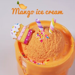 May include: Orange mango ice cream in a yellow cup, topped with colorful sprinkles and two swirled marshmallow candies. A decorative cupcake is on the side. The text "Mango ice cream" is written above the ice cream.