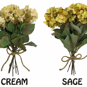 May include: Three bouquets of artificial hydrangea flowers in cream, sage, and mixed colors. Each bouquet is tied with twine.