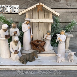 May include: White wooden nativity scene with a white painted barn, a manger, and figurines of Mary, Joseph, baby Jesus, a donkey, a sheep, and three wise men. The scene is on a white wooden base with the words "Wooden Hearts Inc." printed on the front.