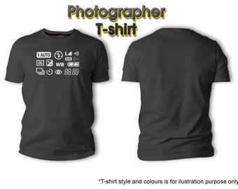 May include: A dark gray t-shirt with a white graphic of camera settings, including "AUTO", "RAW", "WB", and "Err". The text "Photographer T-shirt" is written in yellow above the image.