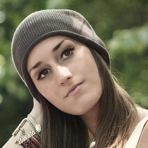 May include: A dark gray knit beanie with a ribbed texture and a folded brim. The beanie is constructed from a fine-gauge knit fabric, featuring a rounded crown that fits closely to the head, providing a simple and functional head covering.