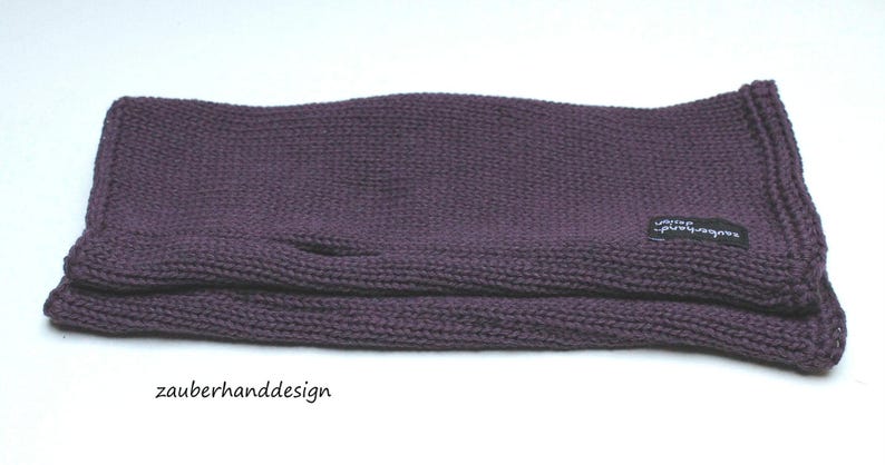 May include: Purple knitted fingerless gloves with a black label that says "zauberhanddesign".