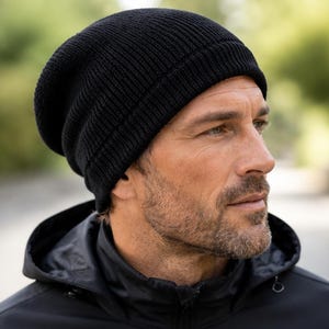 May include: A solid black knit beanie with a ribbed texture and a folded cuff. The hat is constructed from a thick, soft yarn material and features a classic rounded crown shape that fits snugly around the head, providing full coverage.