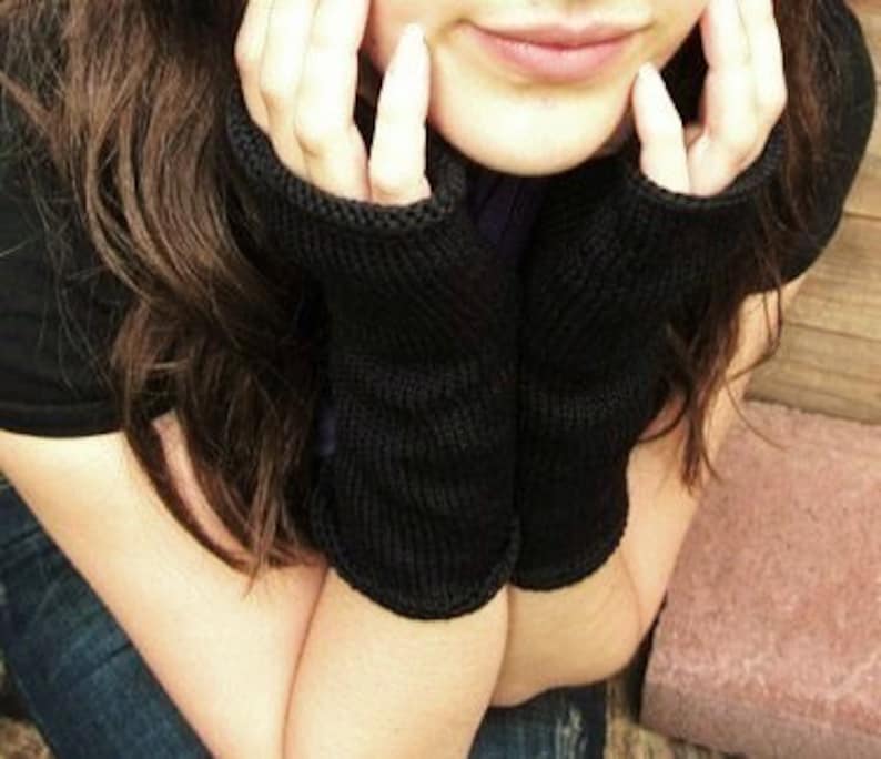 May include: A pair of black knit fingerless gloves with a ribbed texture.