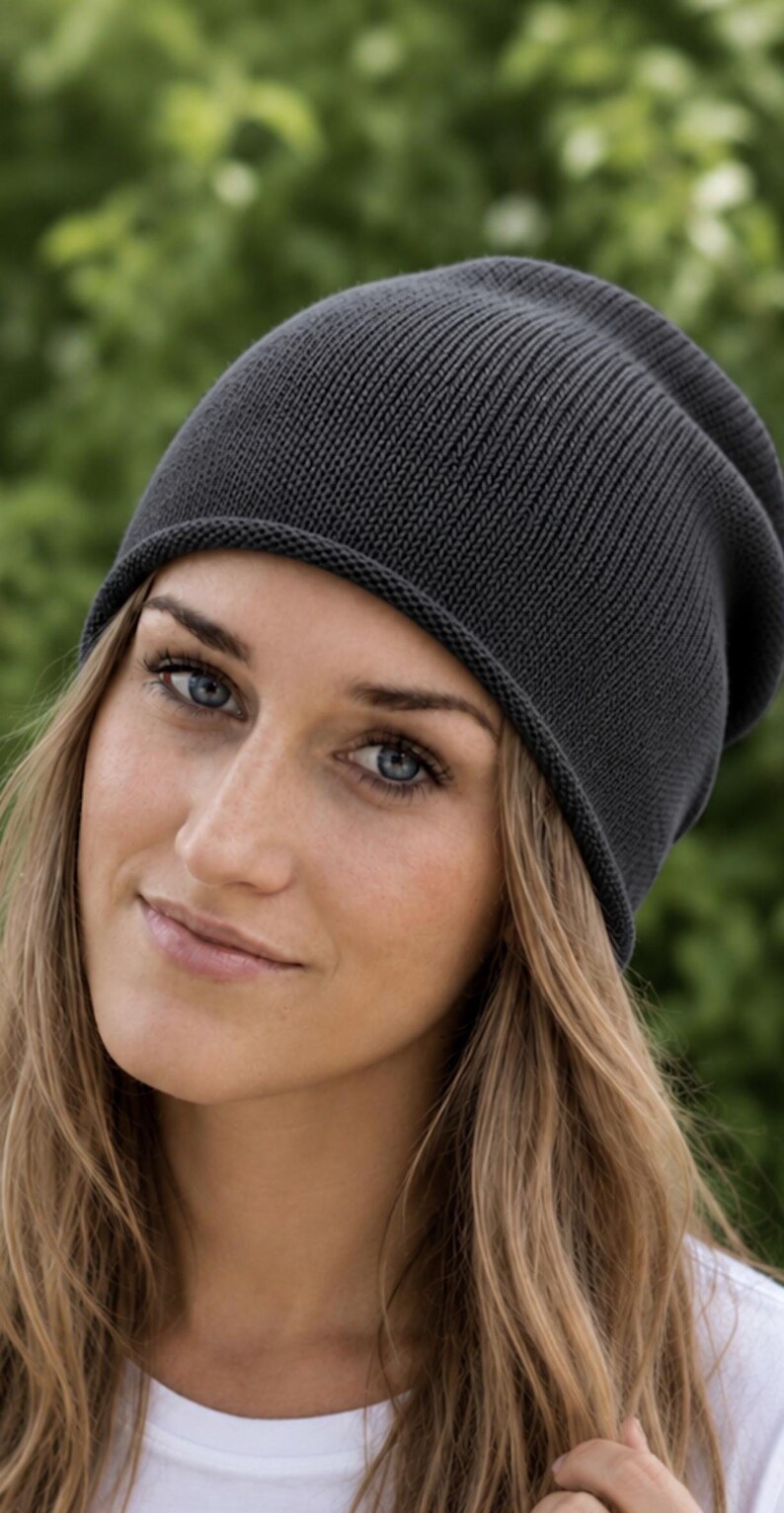 May include: A dark charcoal gray knit beanie with a simple, rounded silhouette and a subtle rolled edge. The hat is constructed from a fine, uniform ribbed knit fabric that provides a smooth texture and a consistent, deep gray color throughout.