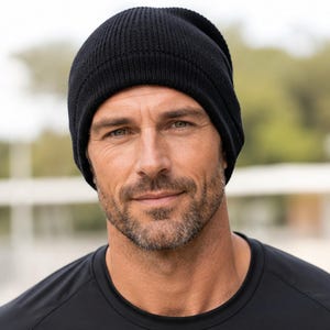 May include: A solid black beanie made of a ribbed knit fabric. The hat features a classic rounded crown design with a folded cuff at the base, providing a snug fit around the head. The material has a consistent dark black color throughout the entire piece.