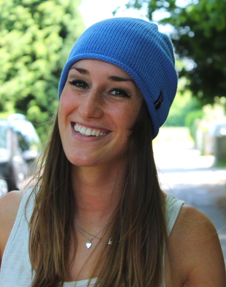 May include: A light blue ribbed knit beanie cap featuring a small dark rectangular brand tag on the side. The hat is constructed with a vertical ribbed texture and a rolled edge, providing a snug fit around the head with a consistent solid color.
