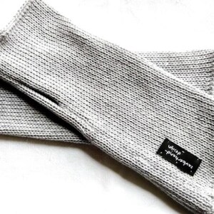 May include: A pair of gray knitted fingerless gloves with a black label that reads "handmade with love".