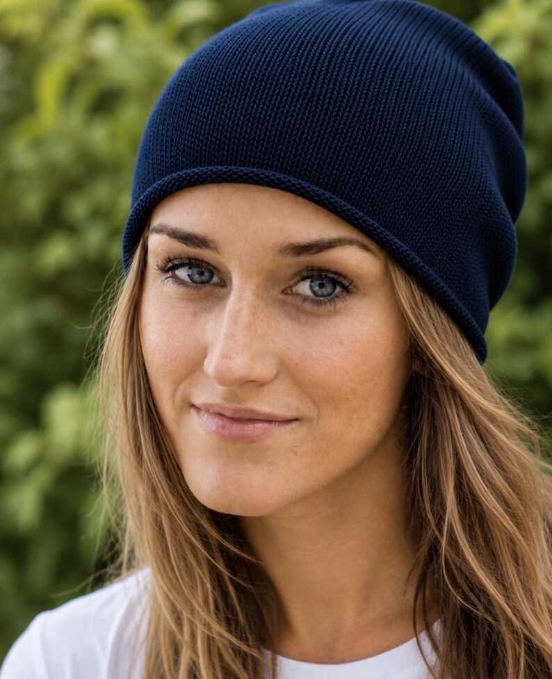 May include: A solid dark navy blue beanie hat featuring a fine-knit texture and a simple rolled edge design. The hat is constructed from a soft, flexible fabric that fits snugly around the head, providing a clean and uniform appearance throughout.