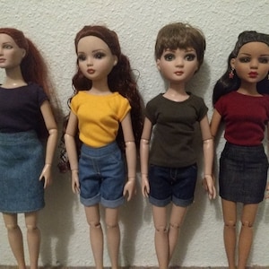 May include: Four fashion dolls wearing different colored t-shirts and denim skirts or shorts. The dolls have long brown or black hair and are wearing earrings.