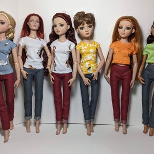 May include: Six dolls wearing different colored tops and jeans. The tops are all short-sleeved and have different patterns. The jeans are all blue and have a cuffed hem.