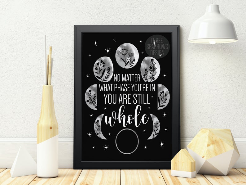 May include: Black and white printable wall art featuring a quote about phases of life and a moon design. The quote reads "No matter what phase you're in you are still whole".