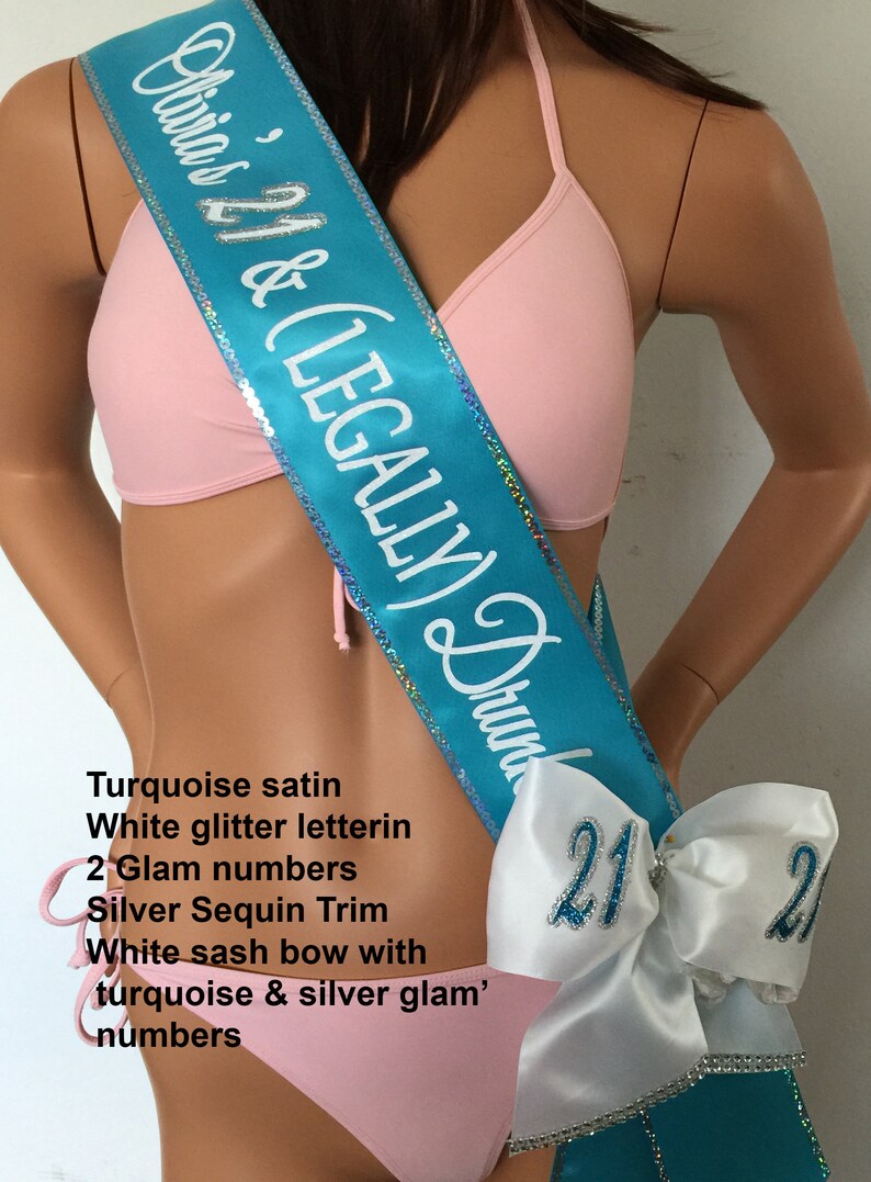 K&ouml;nnte beinhalten: T&uuml;rkiser Satin-Sch&auml;rpe mit wei&szlig;er Glitzer-Beschriftung "Olivia's 21 & (LEGALLY) Drunk". Die Sch&auml;rpe hat einen silbernen Paillettenbesatz und eine wei&szlig;e Schleife mit t&uuml;rkisfarbenen und silbernen Glitzerzahlen.