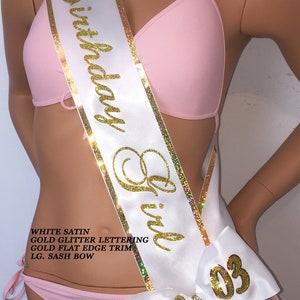 Puede incluir: Sash de sat&eacute;n blanco con letras doradas brillantes que dicen "Birthday Girl" y ribete dorado plano. El sash tiene un gran lazo blanco con letras doradas brillantes que dicen "09 03".