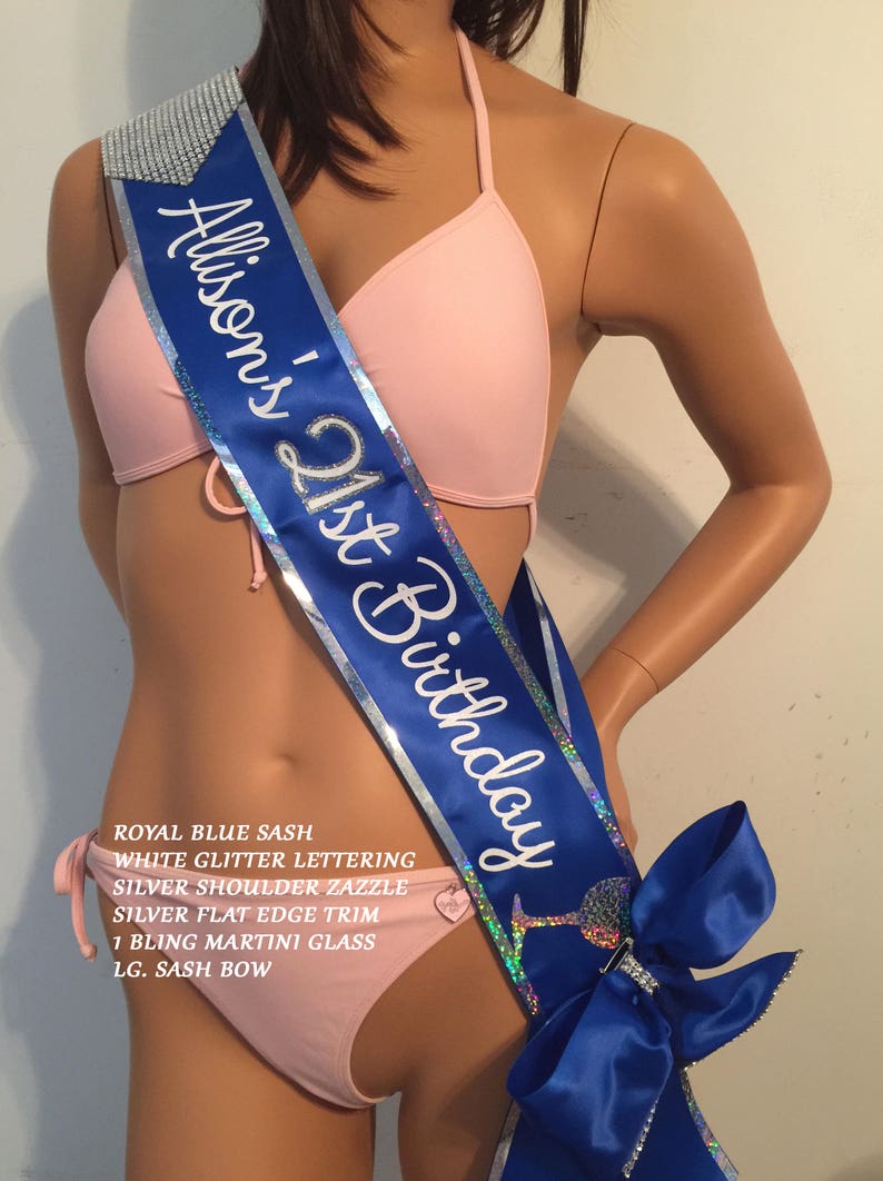 May include: A royal blue satin sash with silver glitter lettering that reads "Allison's 21st Birthday". The sash has a silver shoulder trim, a silver flat edge trim, a bling martini glass charm, and a large blue satin bow.
