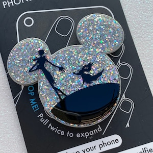 May include: A silver glitter phone grip with a black silhouette of Jack Skellington and Sally from The Nightmare Before Christmas. The grip says "Pop Me! Pull twice to expand" on the back.