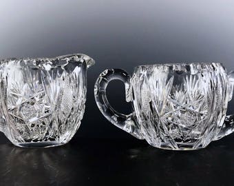 May include: A set of two clear glass sugar and creamer with intricate cut glass designs.