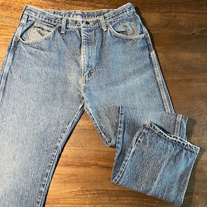 May include: A pair of blue denim jeans with a classic five-pocket style. The jeans have a faded look and are made of a durable cotton blend.