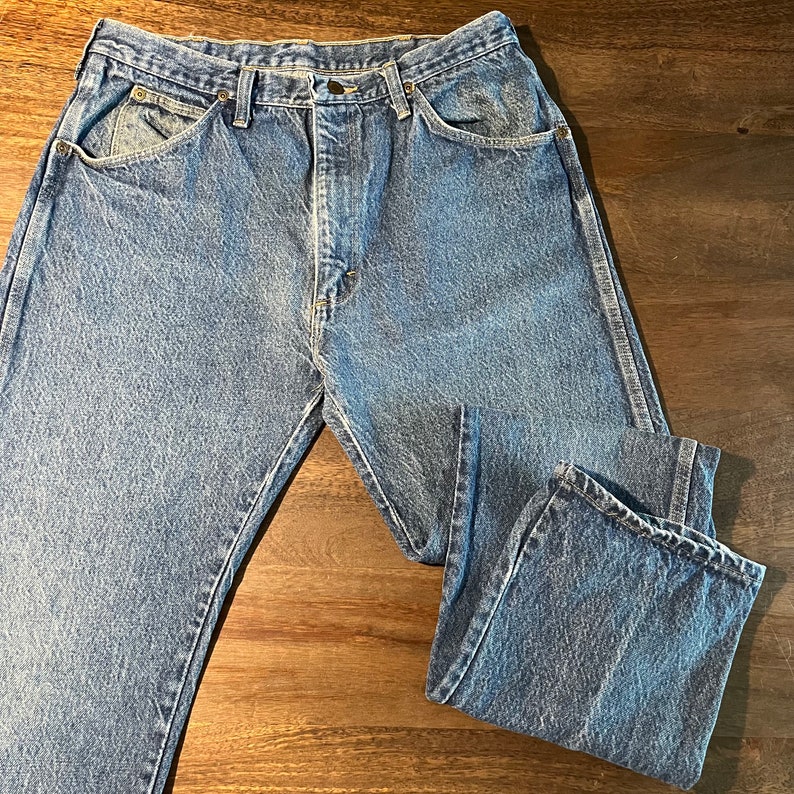 May include: A pair of blue denim jeans with a classic five-pocket style. The jeans have a faded look and are made of a durable cotton blend.