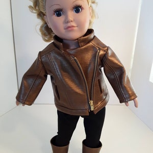 May include: A doll wearing a brown leather jacket, black leggings, and brown boots.