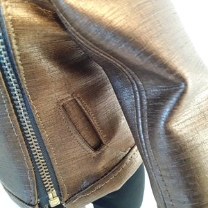 May include: A brown leather jacket with a zipper closure and a small pocket on the sleeve.