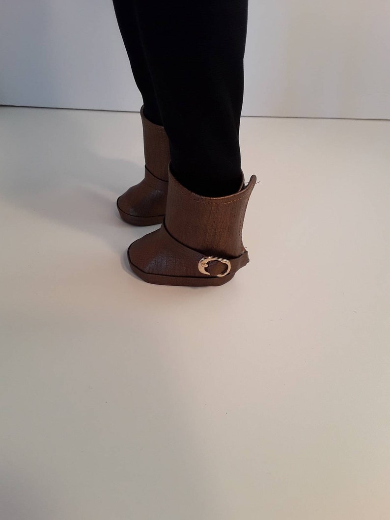 May include: A pair of brown leather boots with a gold buckle. The boots have a slightly pointed toe and a low heel.