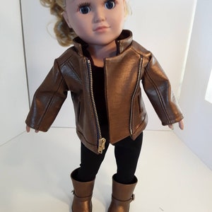 May include: A doll wearing a brown leather jacket, black leggings, and brown boots.