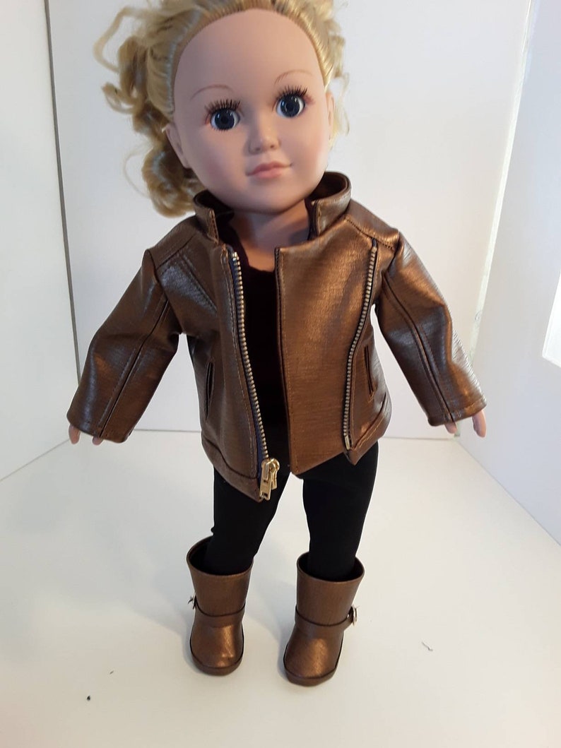 May include: A doll wearing a brown leather jacket, black leggings, and brown boots.