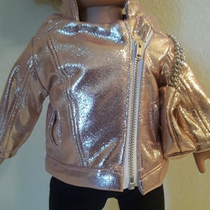 May include: A rose gold metallic jacket with a zip closure. The jacket has a shiny finish and is designed for a doll.