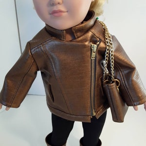 May include: A brown leather jacket with a gold zipper and a gold chain strap purse. The jacket is worn by a doll with blonde hair and blue eyes.