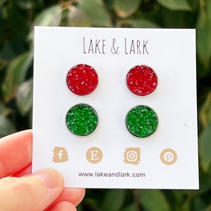 May include: A set of four stud earrings with red and green glitter. The earrings are displayed on a white card with the text "LAKE & LARK" and a website address.