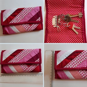 Puede incluir: Un monedero acolchado en tonos rojos, rosas y blancos, con un diseño de patchwork diagonal. El monedero mide aproximadamente 15 cm de largo. El interior es rojo con lunares blancos. Un juego de llaves es visible dentro.