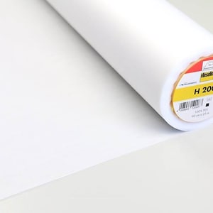 Può includere: Un rotolo bianco di tessuto di interfodera Vlieseline H 200. L'etichetta è gialla con testo nero e un codice a barre in bianco e nero. L'etichetta riporta "Vlieseline H 200 100% PES 90 cm x 25 m."
